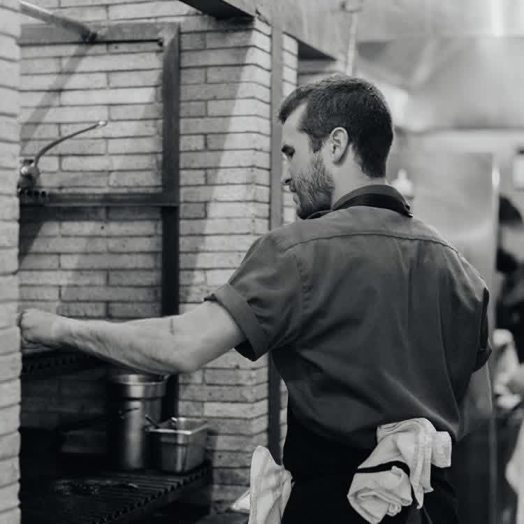 Chef Luke Patton working a brick fire oven